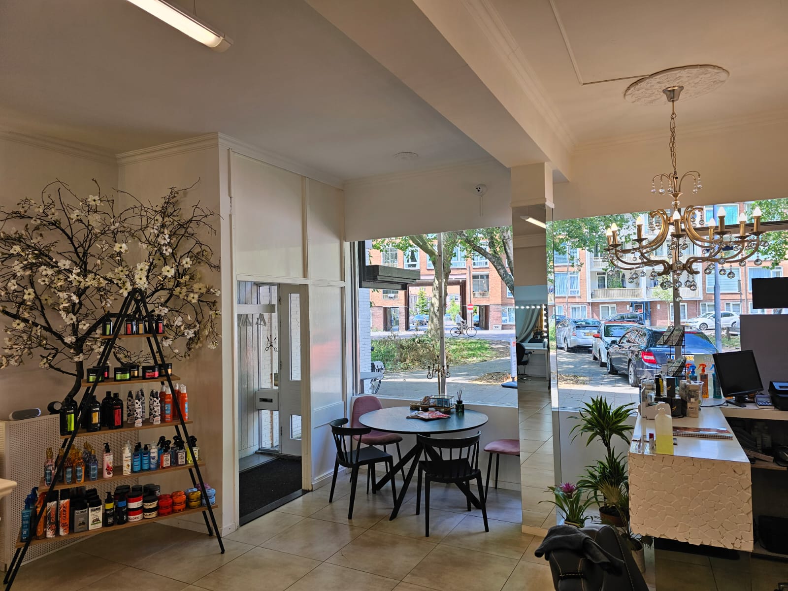 Interieur van Marjinal Salon met kroonluchter, productenkast en zittafel bij het raam