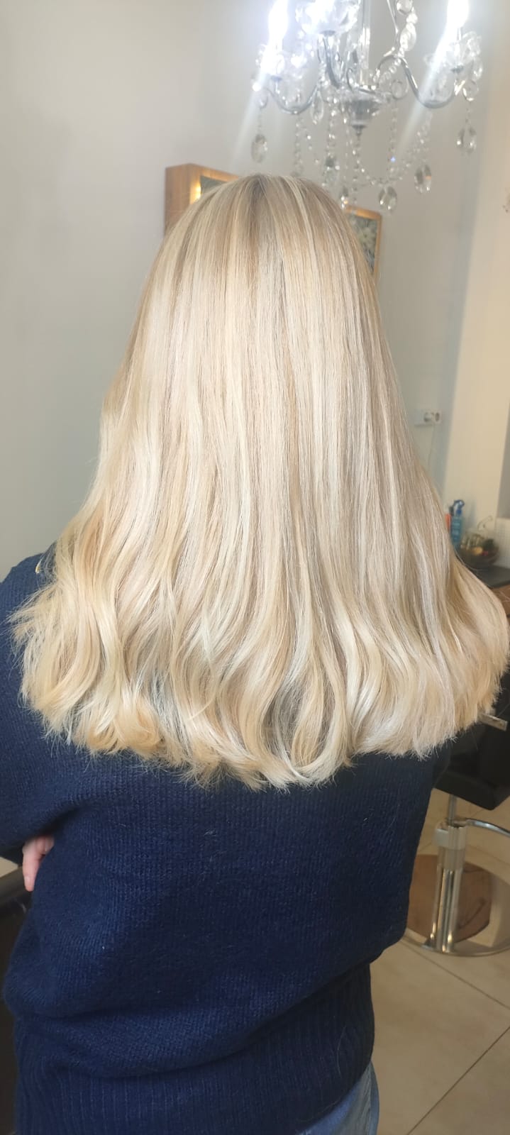 Blond halflang haar van achteren, kroonluchter op de achtergrond